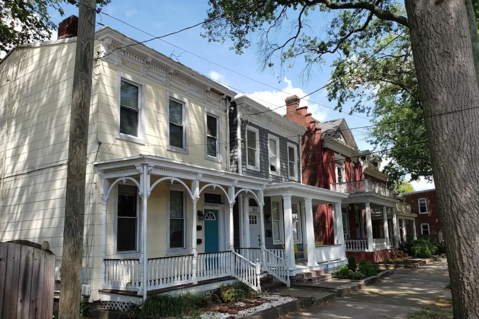 Historic homes with intricate white trim on tree-lined street in Richmond, Virginia.